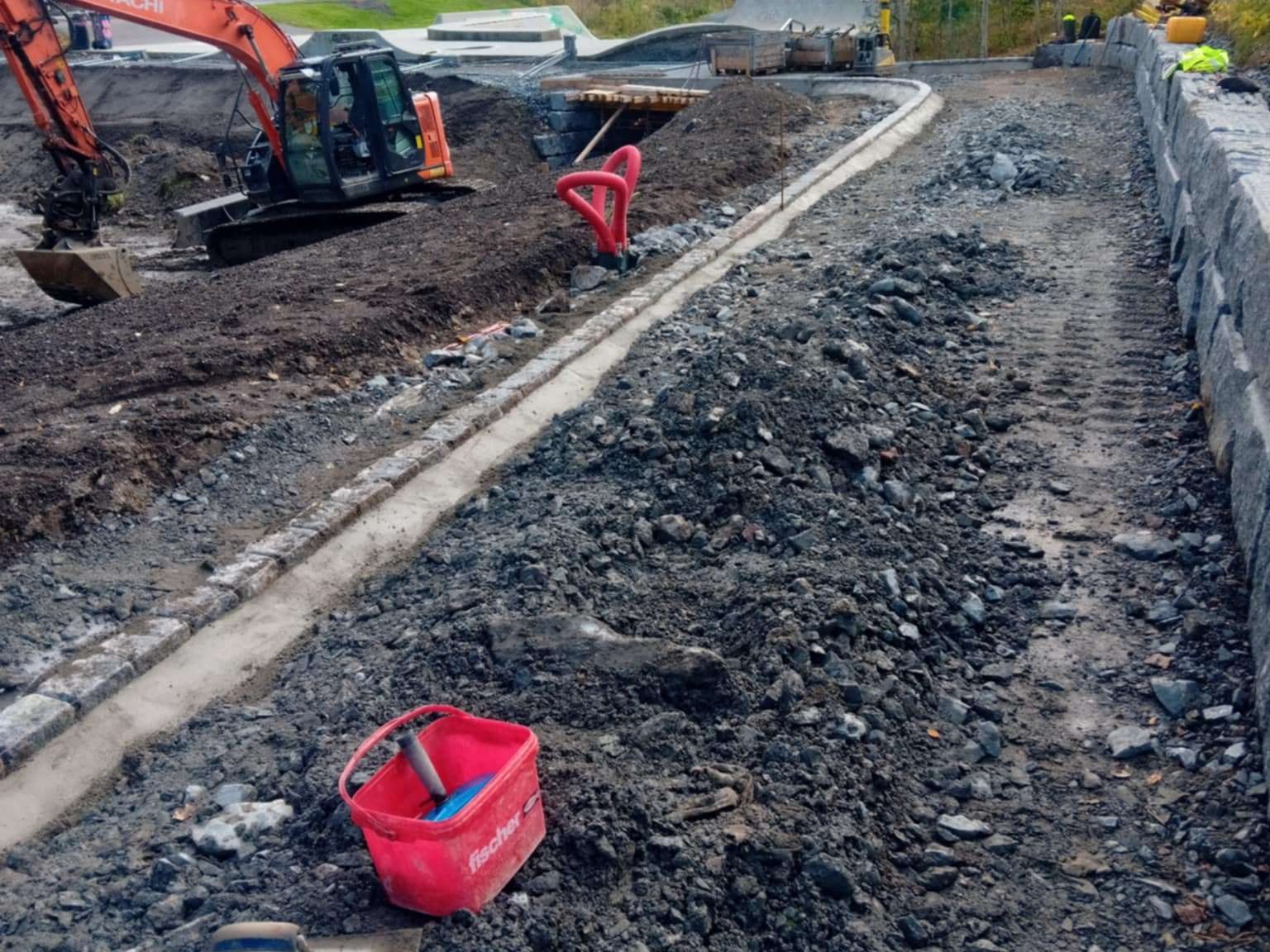 Grunnarbeid for gangvei med kantstein og gravemaskin i bakgrunnen